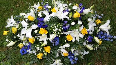 White Lilies with yellow, blue and white flower Coffin Spray