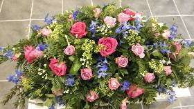 Pink and Cerise Roses with blue, white and green flower Coffin Spray